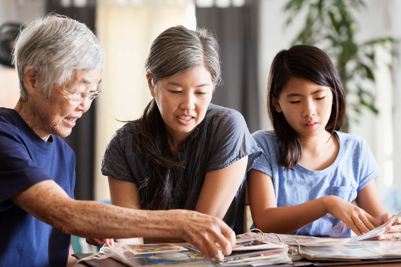 Three generations of Asian women looking at photo album